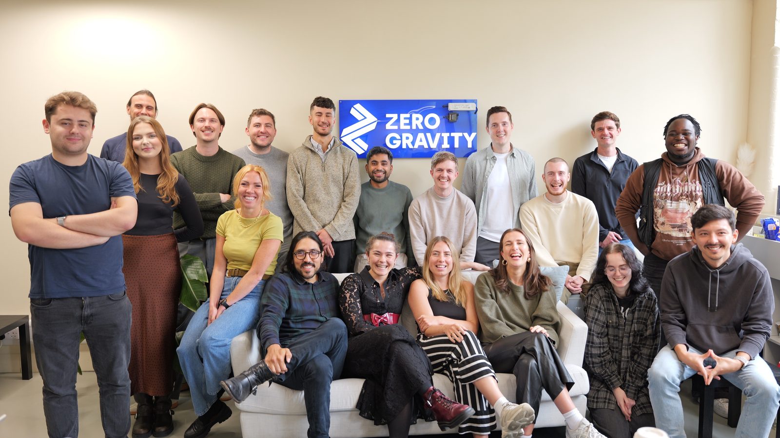 The Zero Gravity team in the office, gathered round a sofa under the company sign